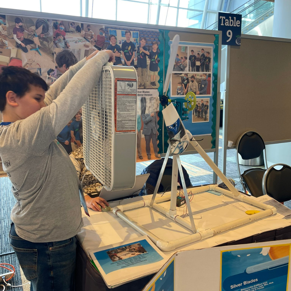 A student holding a fan to activate his turbine generating electricity. 